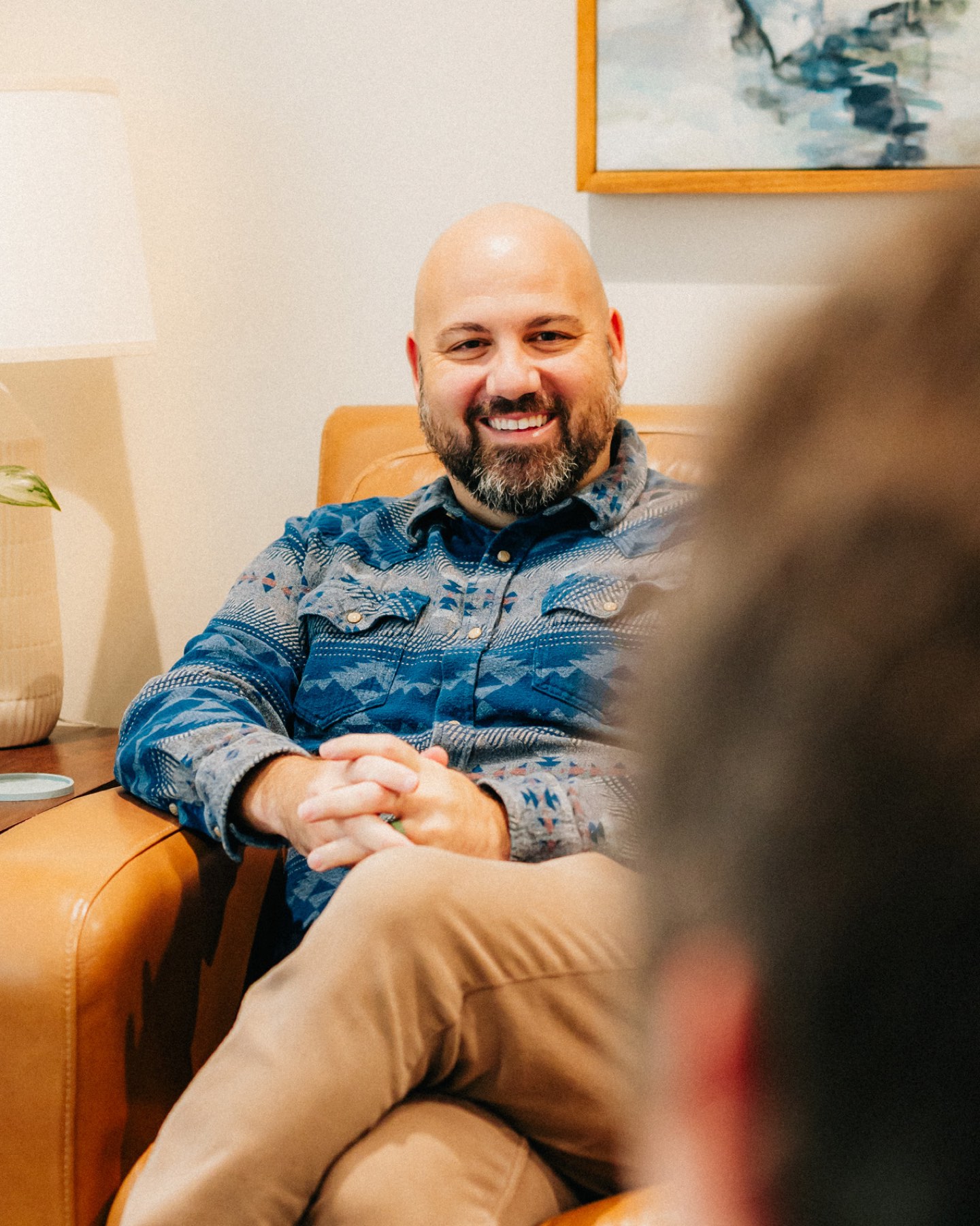 A provider smiling as he listens from a leather armchair