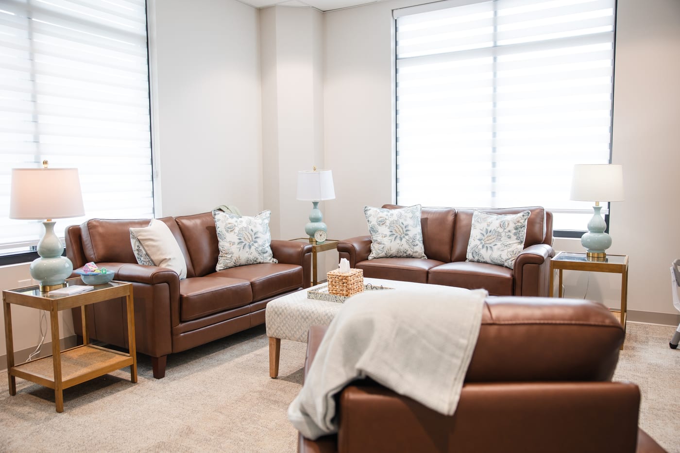 A counseling room with leather sofas, a throw blanket and a table lamp