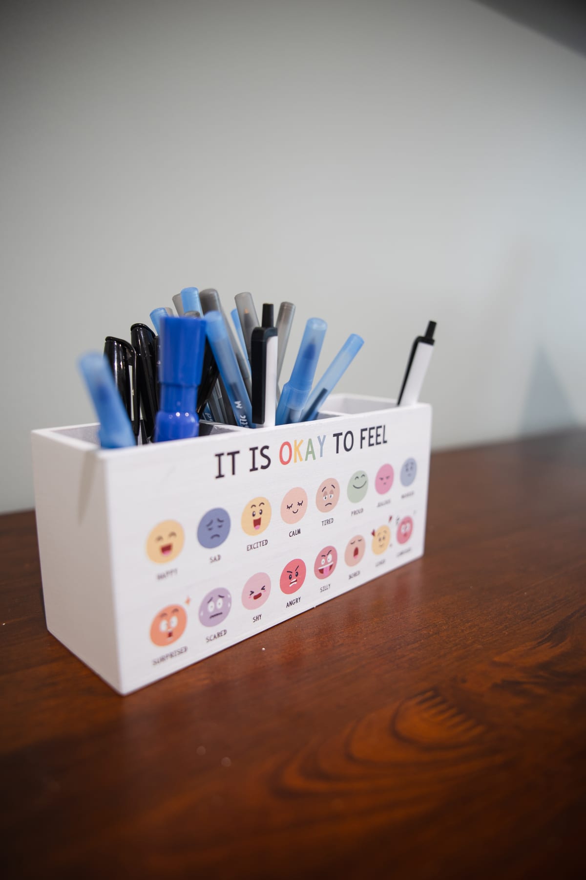 A desk caddy printed with the words It Is Okay To Feel and a row of feelings faces