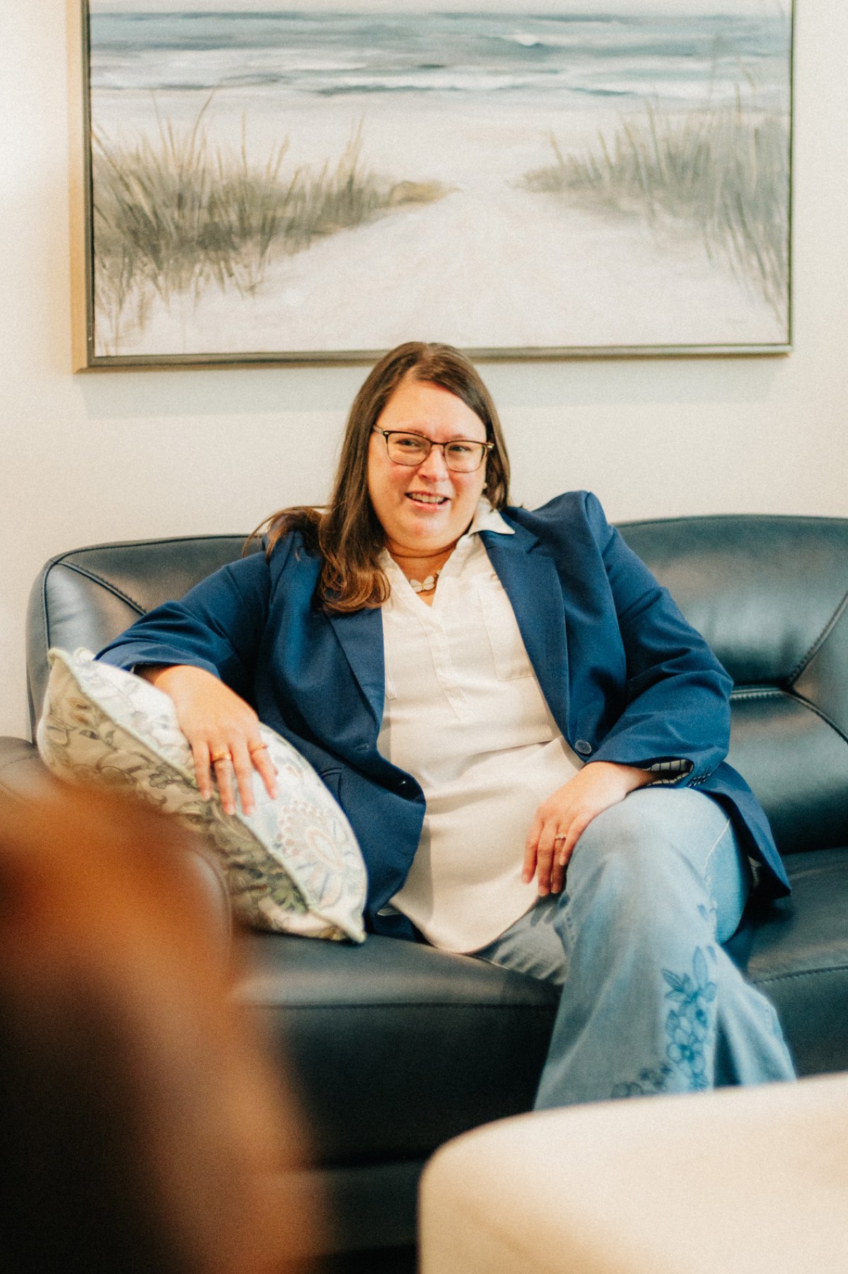 A provider smiling as she listens from a leather sofa