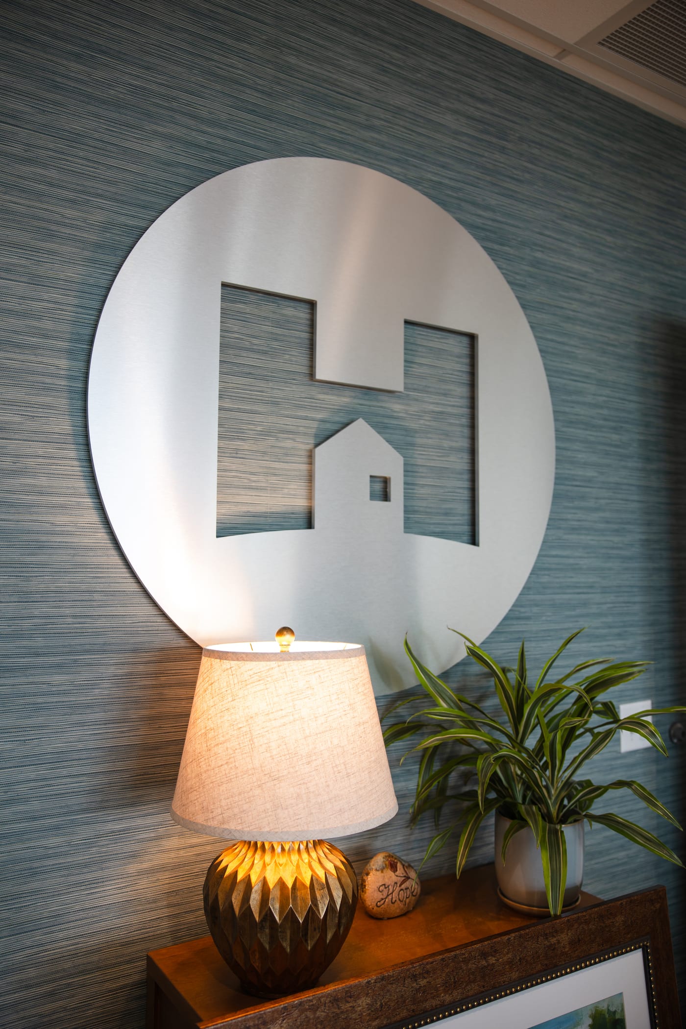 The Hope house-and-H wall mark beside a lit lamp and a green plant
